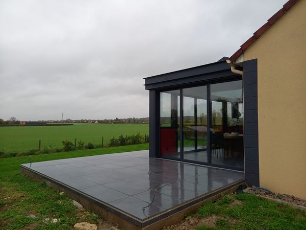 Réalisation d'une maçonnerie de véranda avec une grande ouverture entre les deux pièces de 4 mètres de long une terrasse sur plot