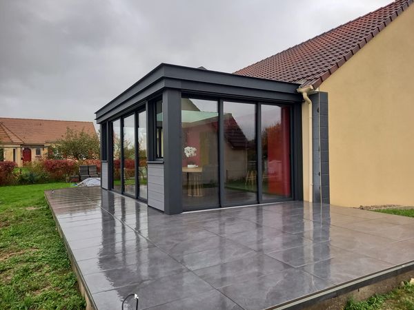 Réalisation d'une maçonnerie de véranda avec une grande ouverture entre les deux pièces de 4 mètres de long une terrasse sur plot