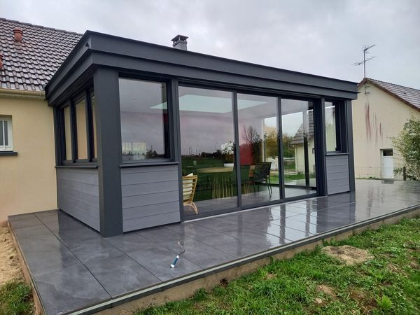 Réalisation d'une maçonnerie de véranda avec une grande ouverture entre les deux pièces de 4 mètres de long une terrasse sur plot